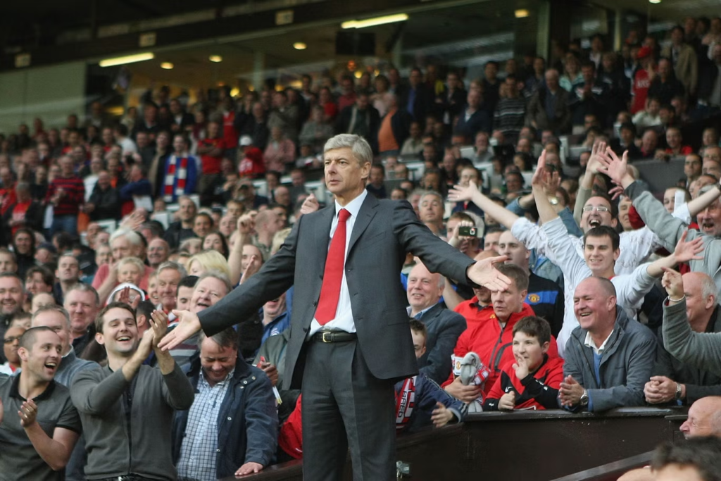 Arsene Wenger stands in the stand at Old Trafford.